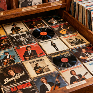 Vintage vinyl records with classic album covers in a wooden crate at a record store