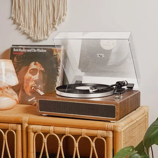 Bluetooth record player with wooden finish on wicker table, vinyl and decor in cozy room