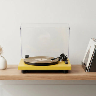 Yellow high-fidelity Bluetooth turntable with vinyl record on wooden shelf, album covers nearby.