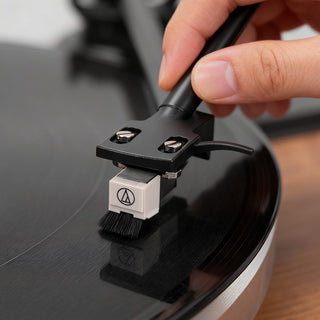 Hand cleaning turntable stylus on a vinyl record for better sound quality