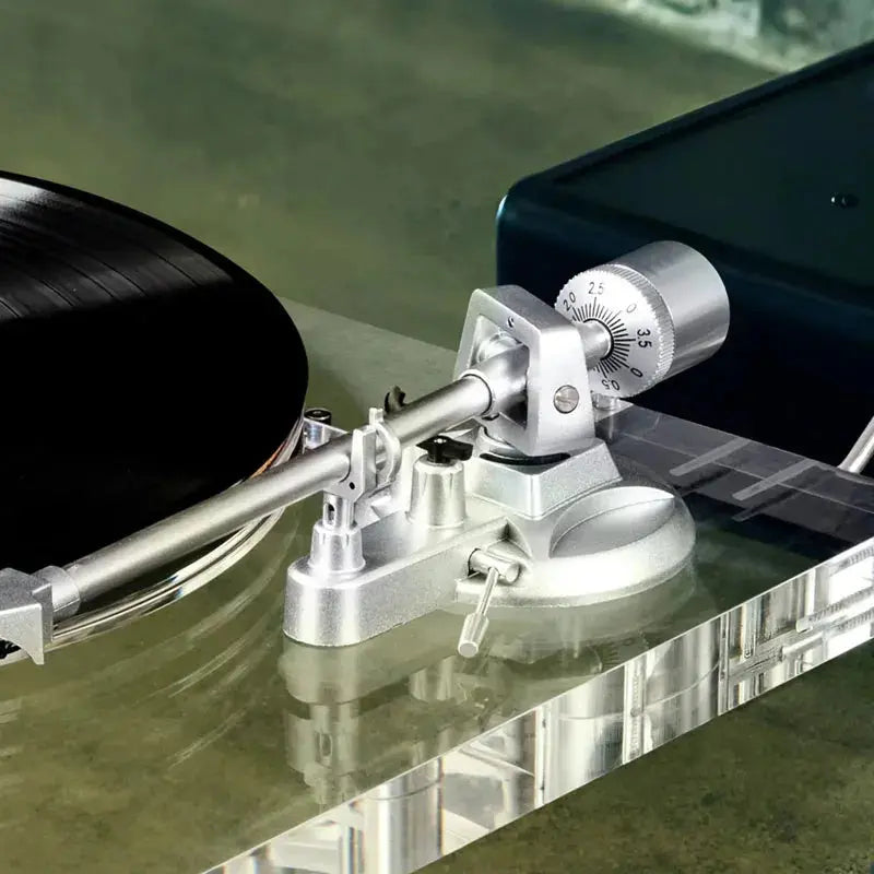 Aluminum tonearm on a clear acrylic turntable with a vinyl record, close-up view