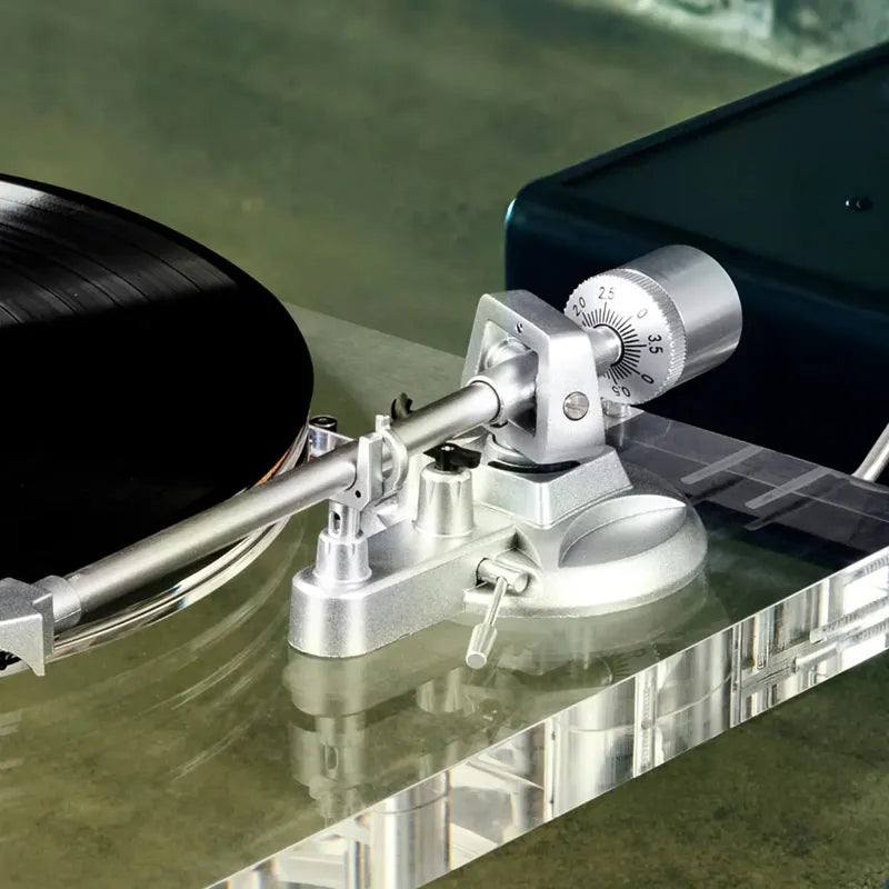 Aluminum tonearm on a clear acrylic turntable with a vinyl record, close-up view