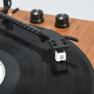 Close-up of a vinyl record player turntable with a wooden base and control knobs