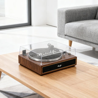 Retro wooden turntable with clear dust cover on a modern coffee table in a bright living room.