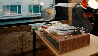 Wooden record player on desk with globe, books, and window background