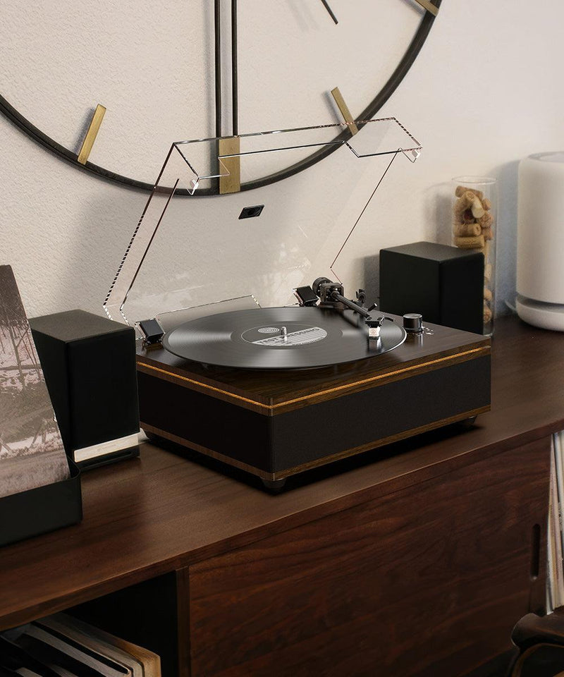 Bluetooth all-in-one record player with speakers on wood console under large wall clock