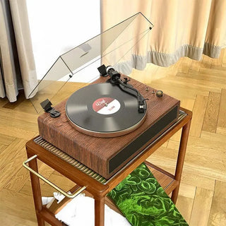 Retro wood all-in-one record player on a wooden stand in a sunlit room with curtains.